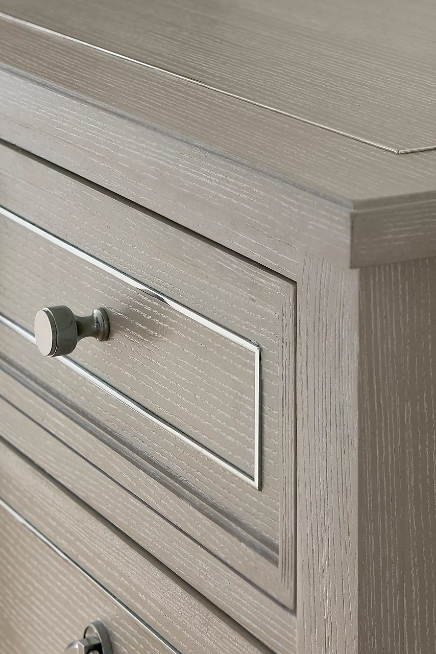 Closeup of a Hyde Park Dresser in Heathered Grey showing the stainless steel hardware in radiant silver finish and the polished silver metal inlay in a room scene.